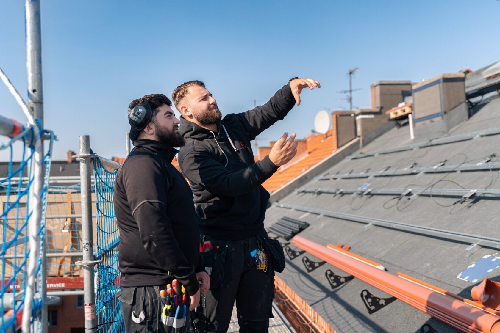 Installation-av-solpaneler-på-brf-tak-i-bild-pekar-elektriker-och-planerar-installtionen